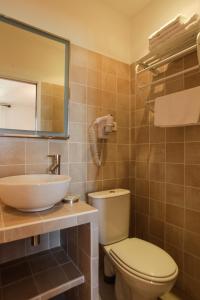 W łazience znajduje się toaleta, umywalka i lustro. w obiekcie Hôtel de la Plage Les Arcades w mieście Algajola