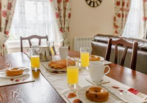 a table with a breakfast of orange juice and donuts at Tracy - Upcott House in Barnstaple