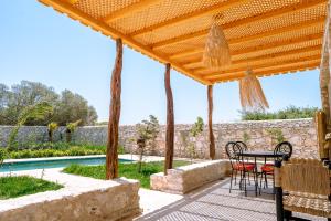 un patio con mesa y sillas bajo una pérgola de madera en villa Floratus, en Essaouira