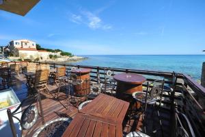 a balcony with tables and chairs and the ocean at Hôtel de la Plage Les Arcades in Algajola
