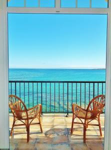 dwa krzesła siedzące na balkonie z widokiem na ocean w obiekcie Hôtel de la Plage Les Arcades w mieście Algajola