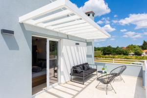 een witte pergola op een patio met stoelen en een tafel bij Villa Ovis in Peresiji