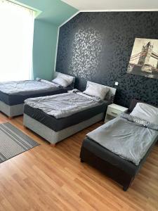 een kamer met drie bedden en een muur bij Velvet Motel in Hegyeshalom