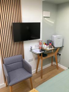 a room with a desk and a chair and a television at Central ensuite guest unit with free parking in Brighton & Hove