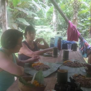 Deux femmes assises à une table avec de la nourriture dans l'établissement Lodging and adventures, à Soposo