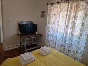 a room with a bed and a television and towels at Alojamento Mercado Norte in Lisbon