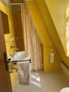 a yellow bathroom with a sink and a shower at Nringrooms Hostel Adenau in Adenau