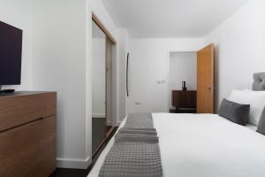 um quarto com uma grande cama branca e uma televisão em Barepta Cove, Stunning Carbis bay apartment em Carbis Bay