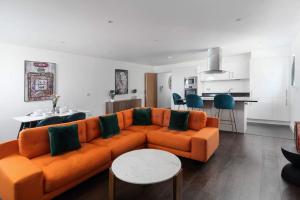 uma sala de estar com um sofá laranja e uma cozinha em Barepta Cove, Stunning Carbis bay apartment em Carbis Bay