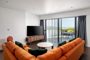 uma sala de estar com um sofá laranja e uma televisão de ecrã plano em Barepta Cove, Stunning Carbis bay apartment em Carbis Bay