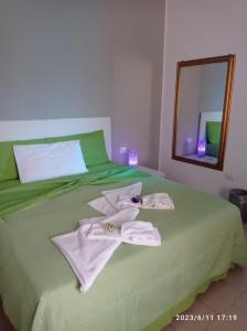 un letto verde con asciugamani e specchio di Villa Benny a Due passi dal mare a Santa Caterina di Nardò