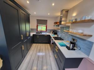 a kitchen with black cabinets and a wooden floor at Teresa's Cottage in Kilcolgan