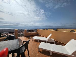 een balkon met tafels en stoelen en uitzicht op de oceaan bij BALCÓN DEL ATLANTICO CALETA de FUSTE in Caleta De Fuste