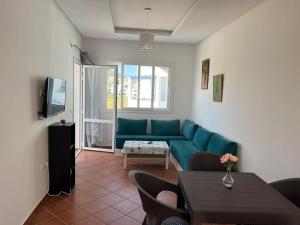 Un bel appartement à Jawhara Smir, Marina Smir في مارينا سمير: غرفة معيشة مع أريكة زرقاء وتلفزيون