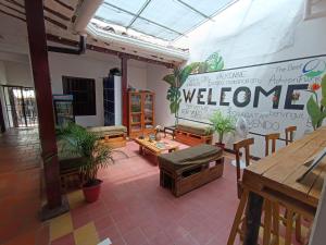 una habitación con bancos y mesas y un cartel de bienvenida en The Best Adventure Hostel, en San Gil
