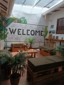 una habitación con plantas y un cartel de bienvenida en la pared en The Best Adventure Hostel, en San Gil