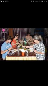little rose inn في ويلاوايا: مجموعة من الناس يجلسون على طاولة يأكلون الطعام
