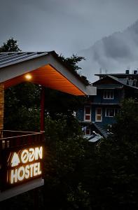un panneau pour une auberge de jeunesse en oxyde devant une maison dans l'établissement Odin Hostel Kasol, à Kasol