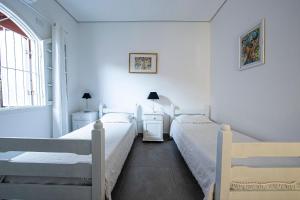 two beds in a room with white walls at Nova, piscina exclusiva, 350 m. de Camburizinho in Camburi