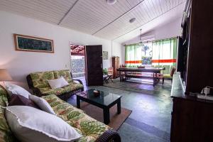 uma sala de estar com um sofá e uma mesa em Piscina e 3 dorm. a 150 m de Camburizinho em Camburi