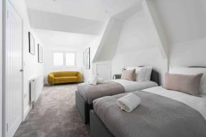 3 Bed, sea views, central Penzance,newly renovated في بينزانس: غرفة بيضاء بسريرين وكرسي اصفر