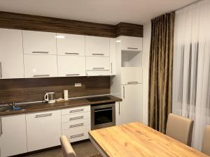 a kitchen with white cabinets and a wooden table at Apartment Paradise Enver in Dubrave Gornje