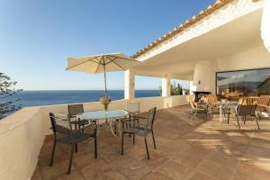 un patio con mesa, sillas y el océano en Villa Lobo, en Salobreña