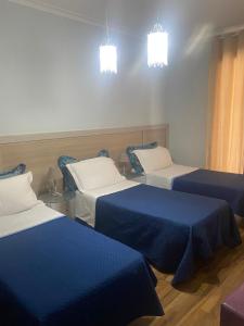 Cette chambre comprend 3 lits avec des draps bleus et blancs. dans l'établissement B&B Elios Rooms, à Catane