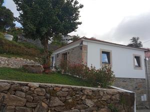 uma casa branca com uma parede de pedra em frente em Casa Tia Vina - Serra em Arouca mais 22 fotografias