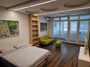 a bedroom with a bed and a green chair at STATUS Superior Apartments in Belgrade