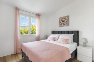 a white bedroom with a large bed with pink pillows at Tonina apartment - house with patio, jacuzzi, free parking in Split