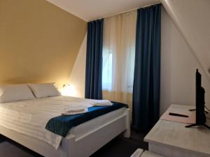 1 dormitorio con 1 cama con cortinas azules y ventana en Pensiunea Happy Inn, en Vatra Dornei