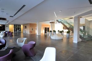 a lobby with white and purple chairs and stairs at AS Hotel Limbiate Fiera in Limbiate