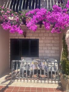 einen Tisch und Stühle mit lila Blumen auf einem Gebäude in der Unterkunft Villa Bougenvilia Tomas in Tučepi