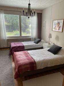 two beds in a bedroom with a chandelier at Omakotitalo 100m2, 3 makuuhuonetta Joensuu in Joensuu