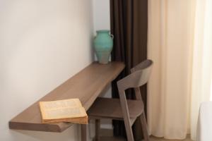 una mesa con un libro y un jarrón y una silla en CeraMio Suites, en Limenas