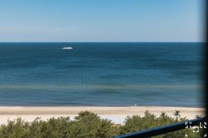 a boat in the ocean next to a beach at Wave Międzyzdroje - Luxury 2 Bedroom Suite with Salon and Kitchen in Międzyzdroje