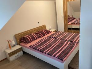 a bedroom with a large bed with a striped comforter at Apartmani G&E in Delnice