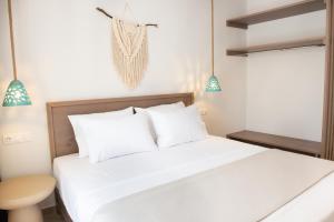 una camera da letto con un letto bianco con cuscini bianchi di CeraMio Suites a Limenas