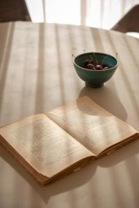 an open book and a bowl of fruit on a table at CeraMio Suites in Limenas +71 photos