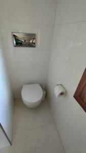a white bathroom with a toilet and a roll of toilet paper at Lovers' Nest in Mesariá