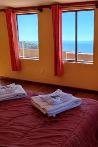 two beds in a room with two windows at Hosteria LAS ISLAS in Comunidad Yumani