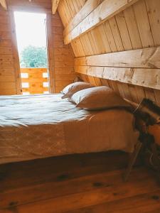 Łóżko w drewnianym pokoju z oknem w obiekcie Le studio du Pressoir w mieście Gisay