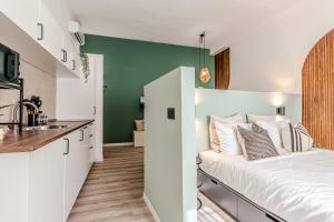 a bedroom with a white bed and a green wall at Japandi, Appartamento Zona Porto Mediceo Livorno in Livorno