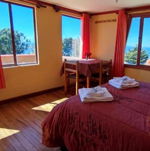 a room with two beds and a table and windows at Hosteria LAS ISLAS in Comunidad Yumani