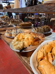 einen Tisch mit Platten aus Gebäck und Kuchen in der Unterkunft CABANAS CHEIRO DE MATO in Cambará