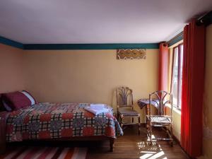 a bedroom with a bed and two chairs and a window at Hosteria LAS ISLAS in Comunidad Yumani