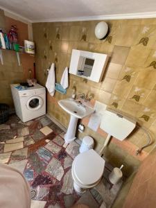 a bathroom with a toilet and a sink and a washing machine at Kariofilli's house in Áyios Athanásios