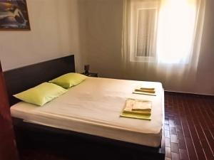a bed with two yellow pillows and a window at Mila Pet friendly house with private beach place in Pag