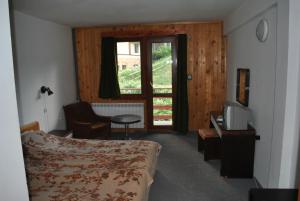 una camera con letto, televisore e finestra di Kris Guesthouse a Stoykite